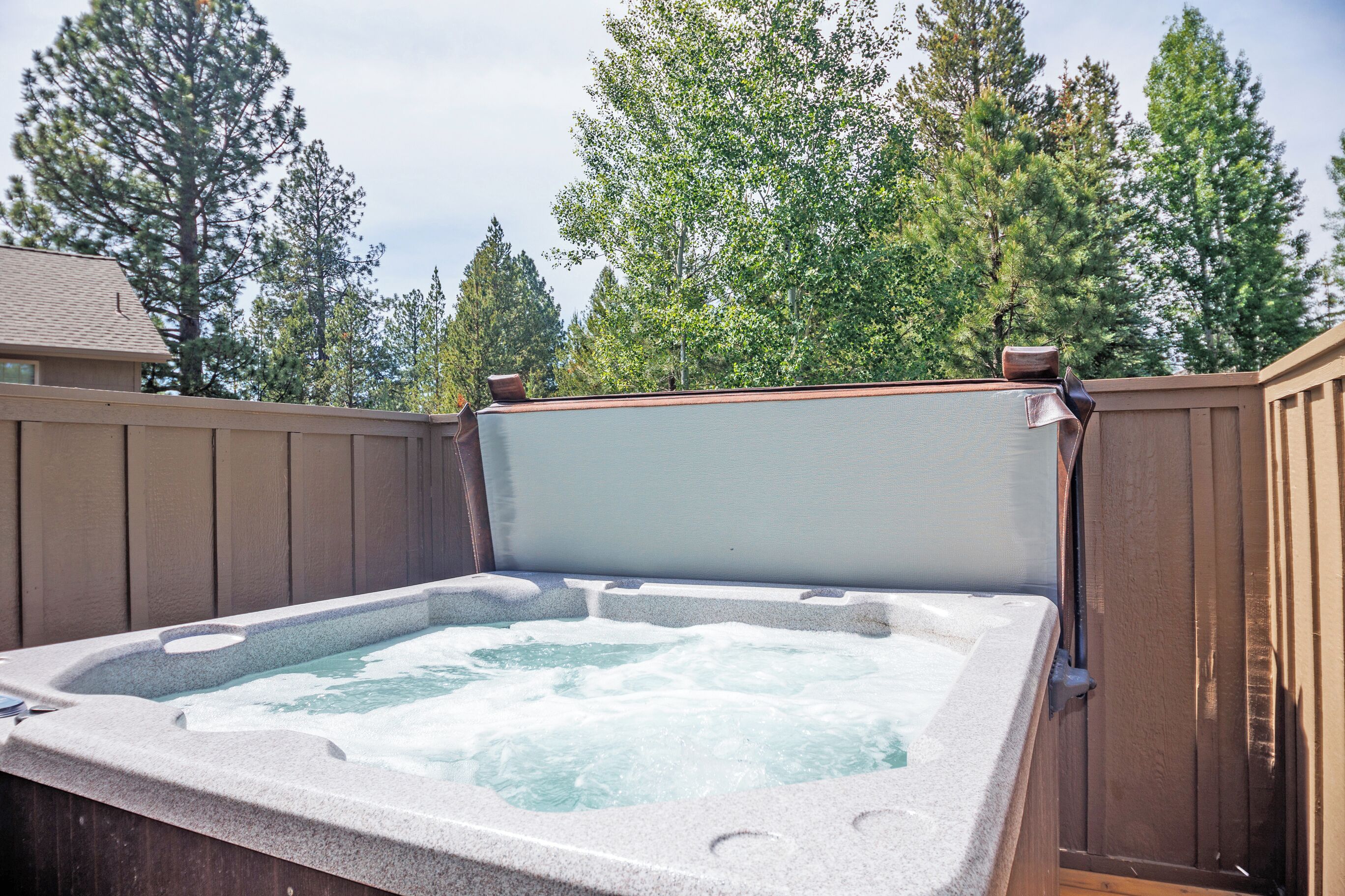 Un bain à remous avec une terrasse en bois et une vue sur les arbres.