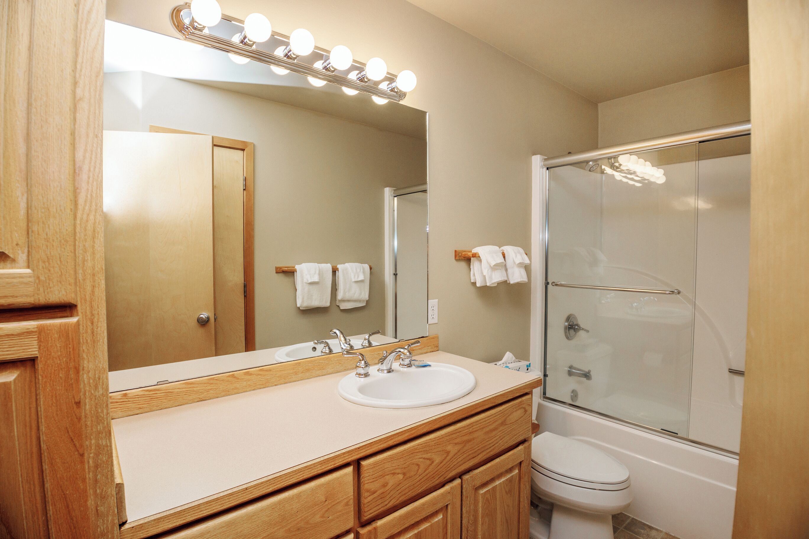 A bathroom with a vanity, sink, mirror, and shower.