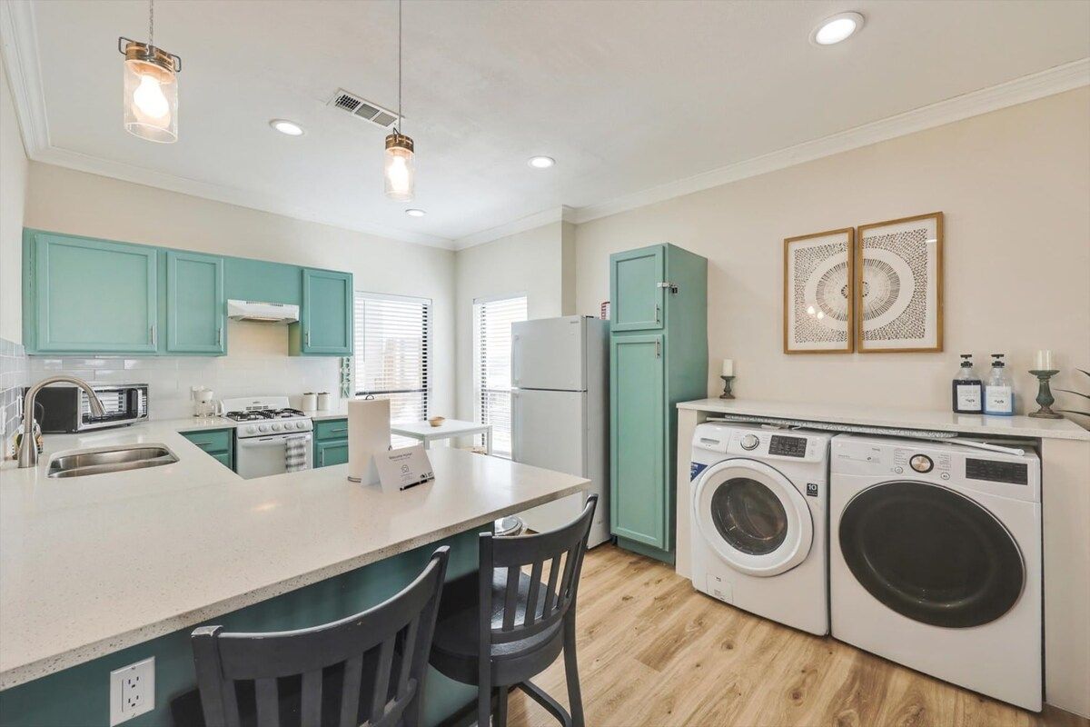 A compact kitchen with a central island, a washing machine, and a microwave.