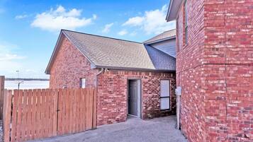 A brick building with a sloped roof, a wooden fence, and a clear sky.