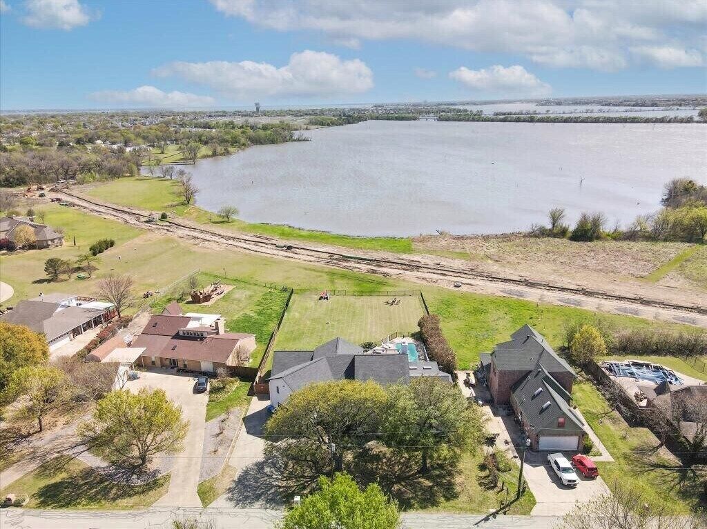 A residential area with houses, a large body of water, and a clear sky.