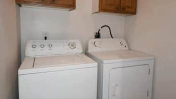 A laundry area with a washer and dryer, wooden cabinets above, and a power outlet on the wall.
