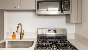 A kitchen with a stainless steel microwave, gas stove, and a gold faucet. - Marbella Lane - Serene Haven Retreat 3BR (Ontario)