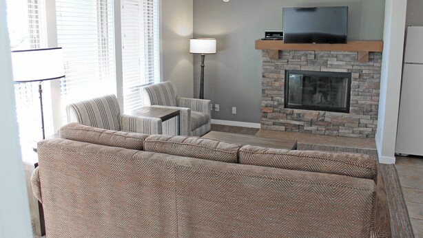 A living room with a sectional sofa, a fireplace, a television, and a lamp.