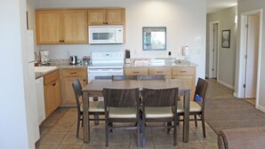 A modern kitchen with wooden cabinets, a microwave, and a dining area with a table and chairs.