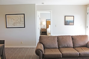 A living room with a brown sofa, a framed picture on the wall, and a carpeted floor. - 7th Mtn 923b (Bend)