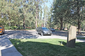 A residential street with parked cars, a grassy area, and trees. - 7th Mtn 923b (Bend)
