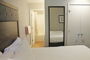 A bedroom with a bed, a door leading to a bathroom, and a wardrobe. - 7th Mtn 923b (Bend)