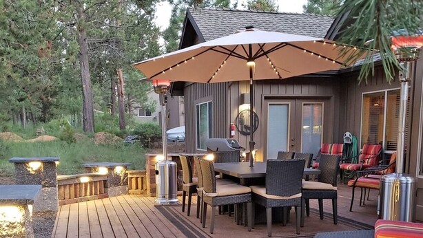 Eine Terrasse mit Gartenmöbeln, einem Grill und Lichterketten.