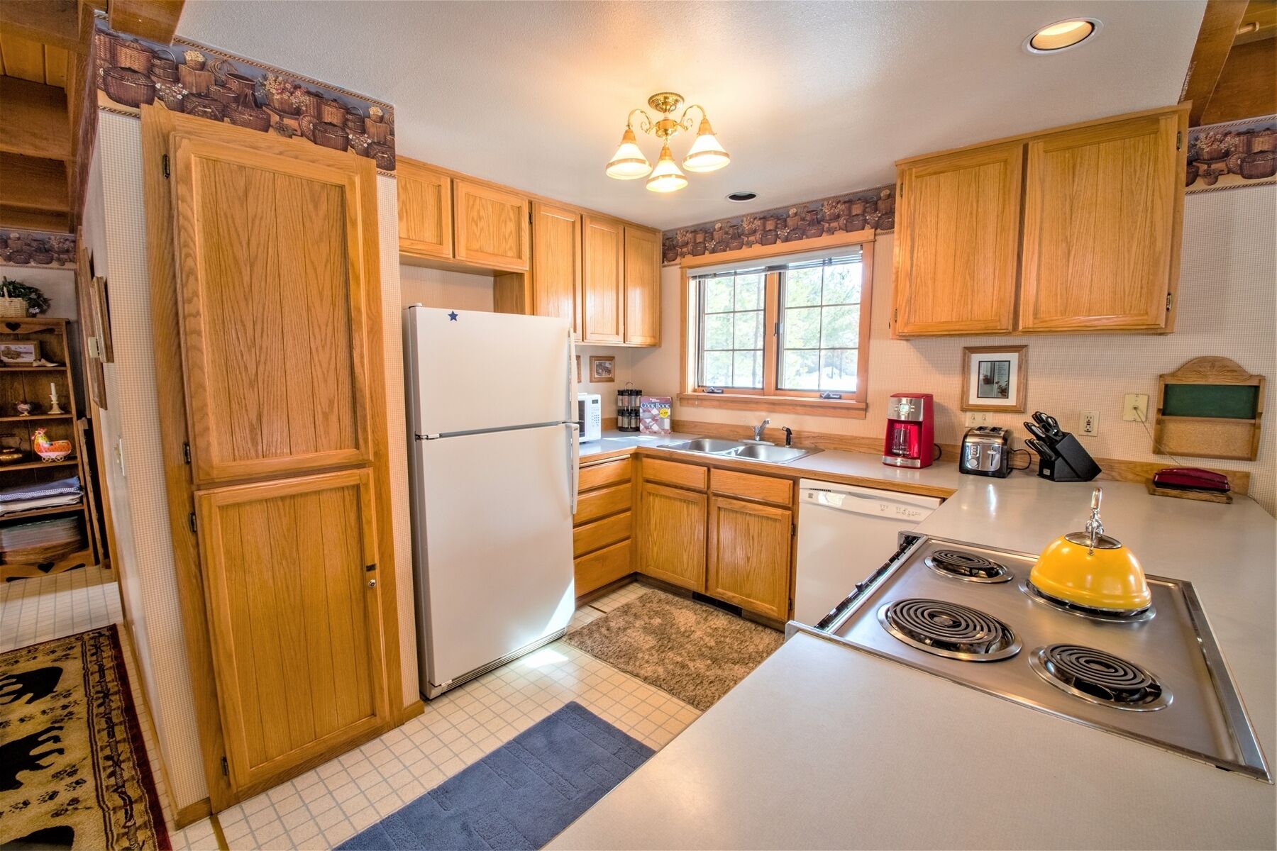 A kitchen with wooden cabinets, a white refrigerator, a stove, and a window providing natural light.