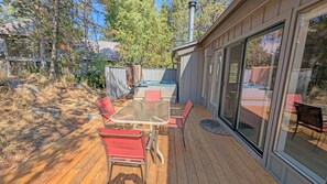 Een terras met een glazen patio, een jacuzzi en een tafel met stoelen.