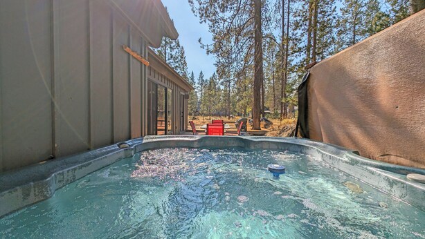 A hot tub area with a view of a building and trees. - Whistling Swan 8 (Bend)