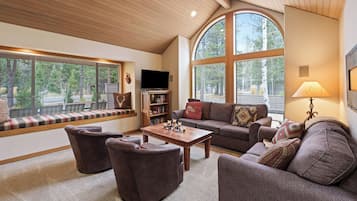 A cozy living room with a large window, a television, a fireplace, and comfortable seating.