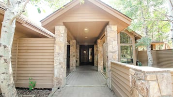 A covered walkway leading to a building with stone pillars and wooden siding.