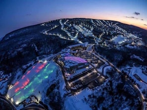 A snow-covered mountainous area with a lit-up building complex and a large illuminated pool. - Lakefront AC Pool Table Kayaks Refined (Tobyhanna)