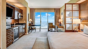 Quarto de hotel com cozinha, área de refeições, cama e uma janela grande com vista.