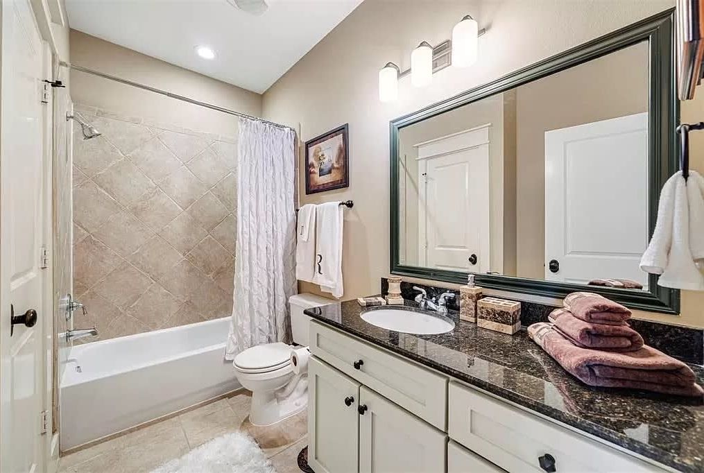 A bathroom with a bathtub, toilet, sink, and a large mirror.