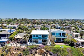 A modern house with a pool, surrounded by a lush garden and a hillside neighborhood. - Oceanfront Neptune Ave Home | Panoramic Views, Luxury Coastal Living, Walk To The Beach (Encinitas)