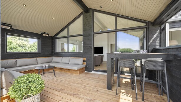 A modern interior with a wooden deck, a built-in sofa, and a bar area. - VillaVilla 958 - Skåstrup Strand, Fyn og øer (Bogense)