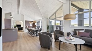Ett rymligt vardagsrum med matbord, soffor och ett köksområde med modern design.