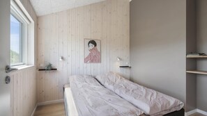 A bedroom with a single bed, wooden panel walls, a window, and a shelf with a plant. - VillaVilla 958 - Skåstrup Strand, Fyn og øer (Bogense)