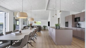 A modern kitchen with a central island, built-in appliances, and pendant lighting. - VillaVilla 958 - Skåstrup Strand, Fyn og øer (Bogense)