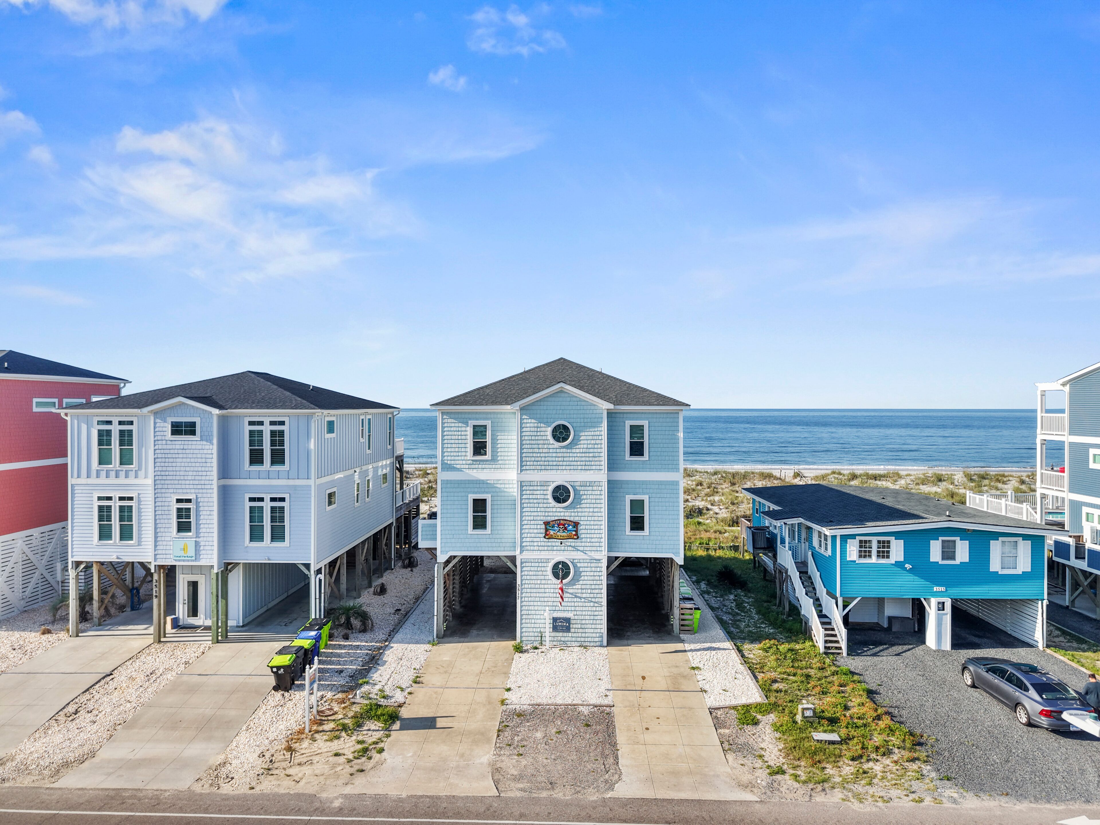 A beachfront property with a central building featuring a large garage and a sign indicating a restaurant.