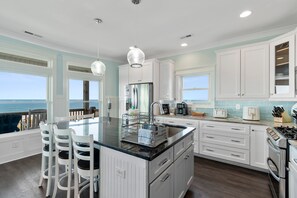 A kitchen with a large island, white cabinetry, and a view of the ocean. - Jolly Rogers: Oceanfront Paradise with Pool, Sleeps 20, 7 bed/ 5.5 bath and two kitchens! (Oak Island)