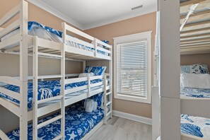 A bunk bed room with a window, white walls, and a beige floor. - Jolly Rogers: Oceanfront Paradise with Pool, Sleeps 20, 7 bed/ 5.5 bath and two kitchens! (Oak Island)
