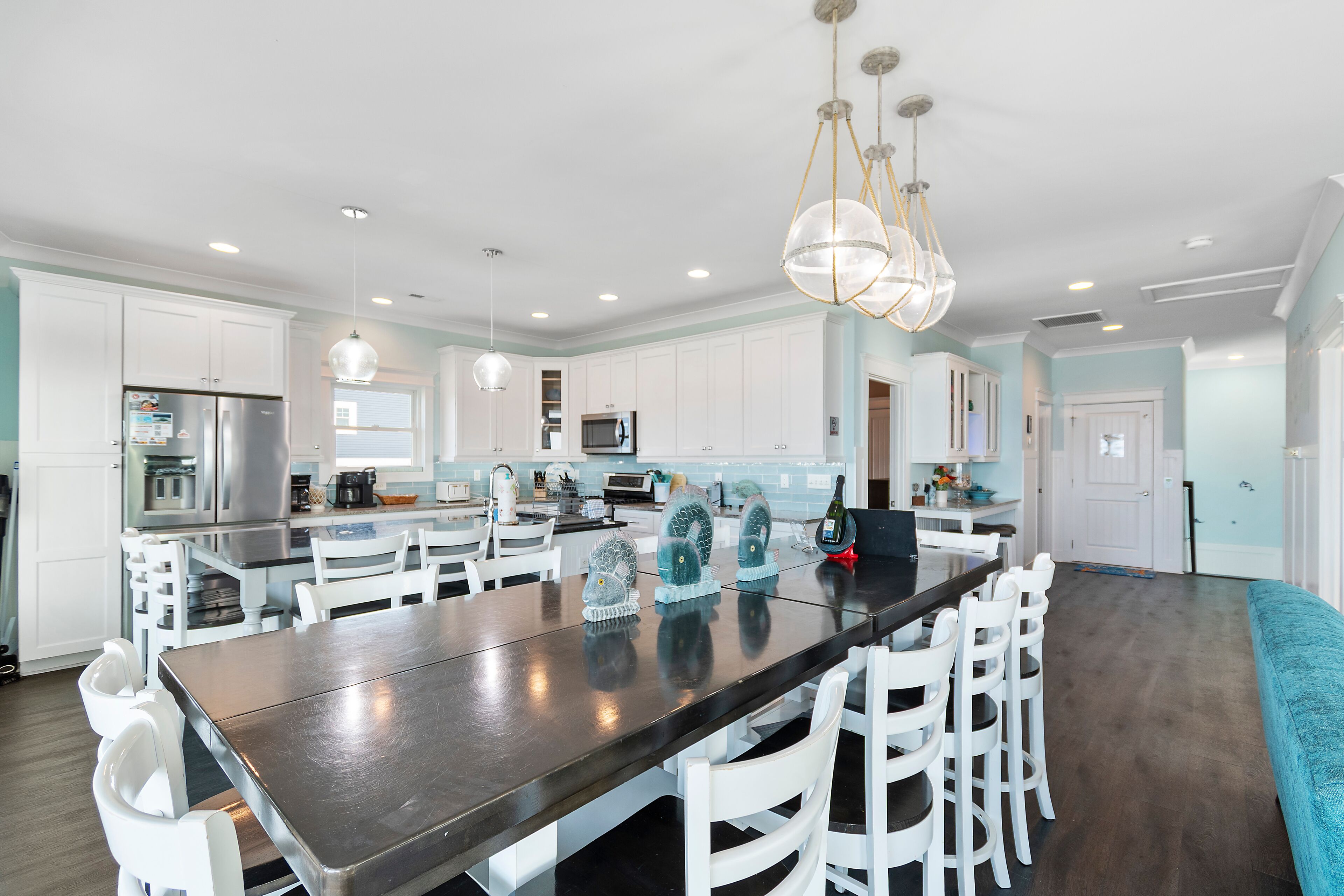 A modern kitchen with white cabinets, a central island, and a chandelier.