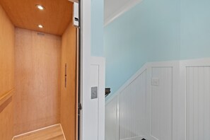 A room with wooden panel walls, a white door, and a light blue wall. - Jolly Rogers: Oceanfront Paradise with Pool, Sleeps 20, 7 bed/ 5.5 bath and two kitchens! (Oak Island)