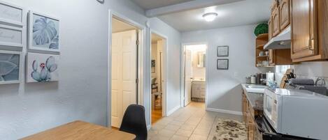 A compact kitchen with a dining area, wooden cabinets, a refrigerator, and a microwave.