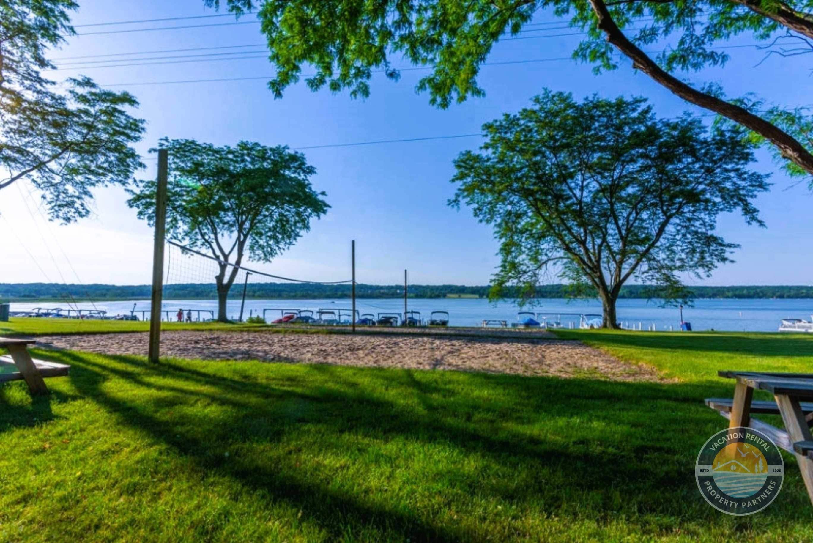 A lakeside view with picnic tables, a dock, and boats.