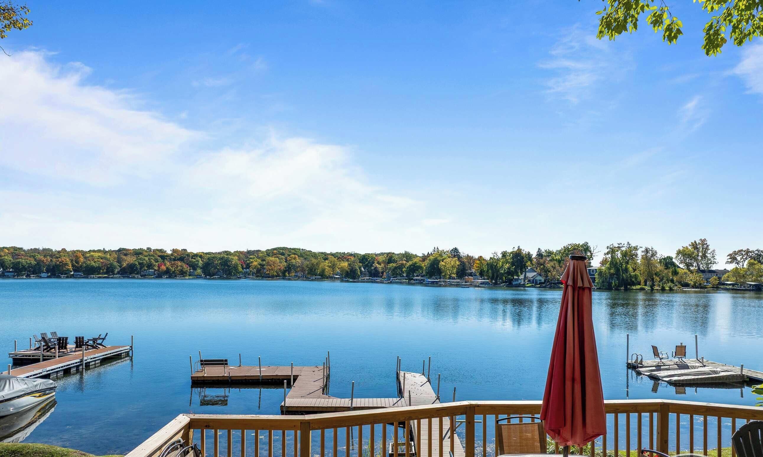 A deck with a view of a calm lake, docked boats, and a logo for vacation rental property partners.