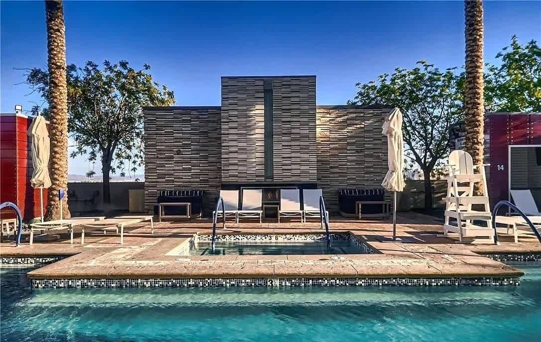 A pool area with a modern design, including a rectangular pool, lounge chairs, and palm trees.