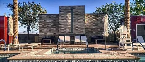 A pool area with a modern design, including a rectangular pool, lounge chairs, and palm trees.