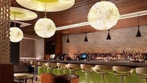 Een bar met verschillende krukken en een zithoek met tafels en stoelen.