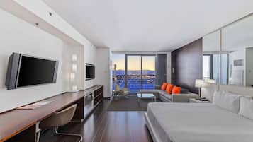Habitación de hotel moderna con una cama grande, un escritorio, un televisor y vistas a la ciudad.