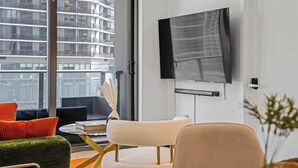 A modern living room with a large window, a flat-screen TV mounted on the wall, and a comfortable seating area with a sofa and armchairs. - Downtown Miami 2BR Skyline Bay View Balcony Corner Suite Luxepad (Miami)