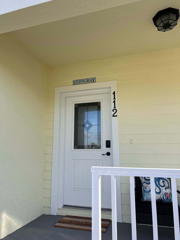 A white door with a frosted glass window, a 'Stingray' sign above, and the number '112' on the wall. - The Stingray Glide Into Your Beach Adventure! (Punta Gorda)
