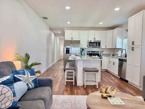A modern kitchen with white cabinets, a central island, and stainless steel appliances. - The Stingray Glide Into Your Beach Adventure! (Punta Gorda)