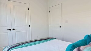 A bedroom with a bed, white walls, and two white doors with black handles. - Seahorse Drift Away in Coastal Comfort (Punta Gorda)