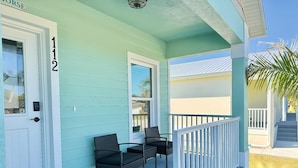 A turquoise house with a porch, number 112, featuring two chairs and a small table. - Seahorse Drift Away in Coastal Comfort (Punta Gorda)