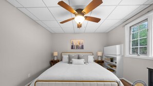 A bedroom with a bed, ceiling fan, artwork, bedside lamps, and a TV. - Lake Como Condo With Lake Views and Pool (Lake Geneva)