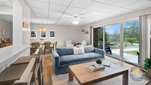 A modern living room with a sofa, coffee table, and dining area. - Lake Como Condo With Lake Views and Pool (Lake Geneva)