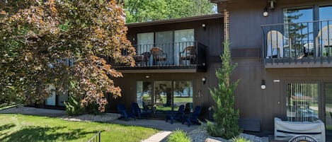 Un immeuble de deux étages doté d’un balcon au niveau supérieur, d’un espace extérieur aménagé pour s’asseoir et d’une enseigne indiquant qu’il s’agit d’une propriété proposée en location de vacances.