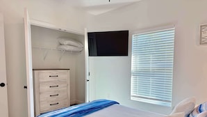 Ein Schlafzimmer mit einem Bett, einem Kleiderschrank, einem Fenster mit Jalousien und einer Tür.