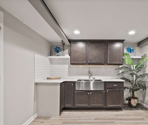 A modern kitchen with dark wood cabinets, white subway tiles, and a stainless steel sink.