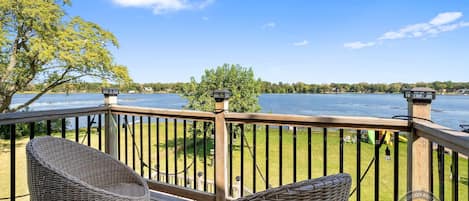 A wooden deck with wicker chairs overlooking a lake.