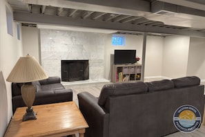 A modern living room with a fireplace, leather sofas, a wooden coffee table, and a television on a stand.